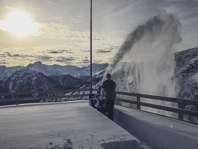 Ein Mann schleudert Neuschnee von der Terrasse der Gruobenalp mit einer Schneefräse. | © Davos Klosters Mountains