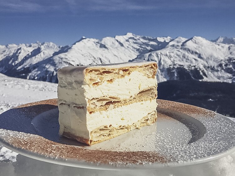 Die legendäre Cremeschnitte der Gruobenalp mit traumhaftem Bergpanorama im Hintergrund. | © Davos Klosters Mountains