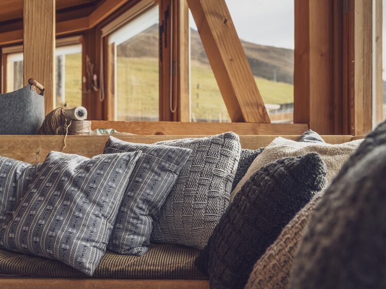 Auf der Bank in der Gaststube auf der Clavadeler Alp liegen selbst genähte und selbst gestrickte Kissen. | © Davos Klosters Mountains