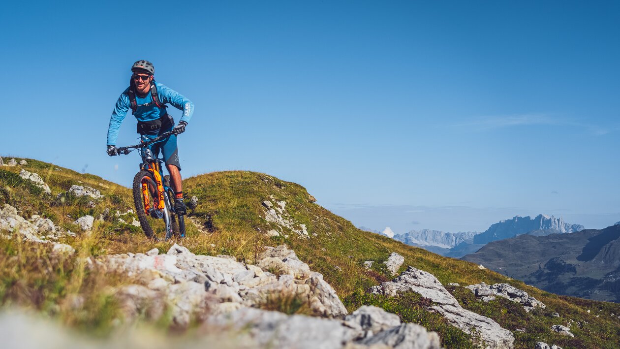 Biker in blauer Kleidung und mit orangem Mountainbike auf Gotschna Parsenn. | © Davos Klosters Mountains