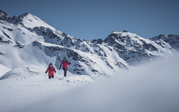 Two senior citizens walk up Pischa on snowshoes. | © Davos Klosters Mountains