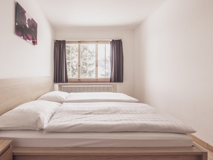 Doppelbettzimmer mit Bettwäsche und Nachttischschränkchen  | © Davos Klosters Mountains 